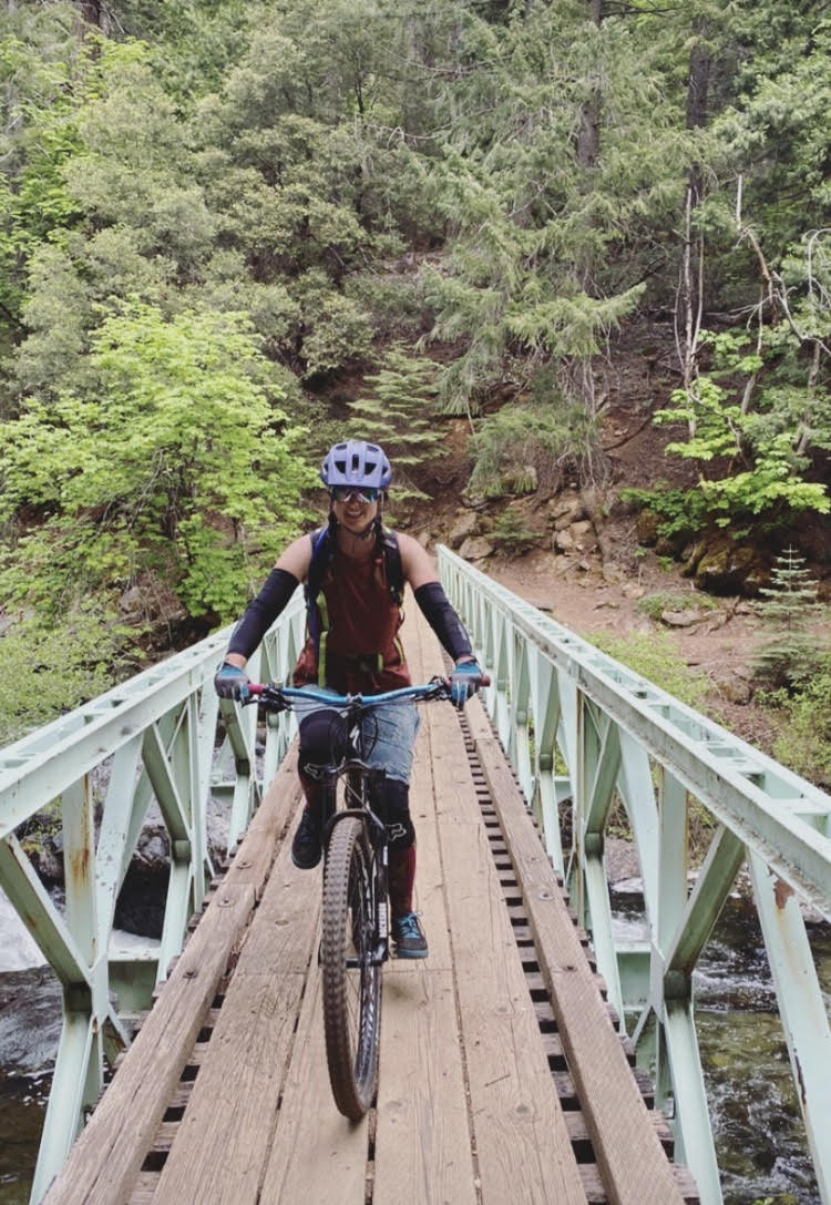 Photo of a program coach mountain biking over a bridge