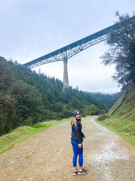 photo of a counselor hiking in a green area near a bridge