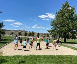 Campers playing outdoor volleyball with coaches