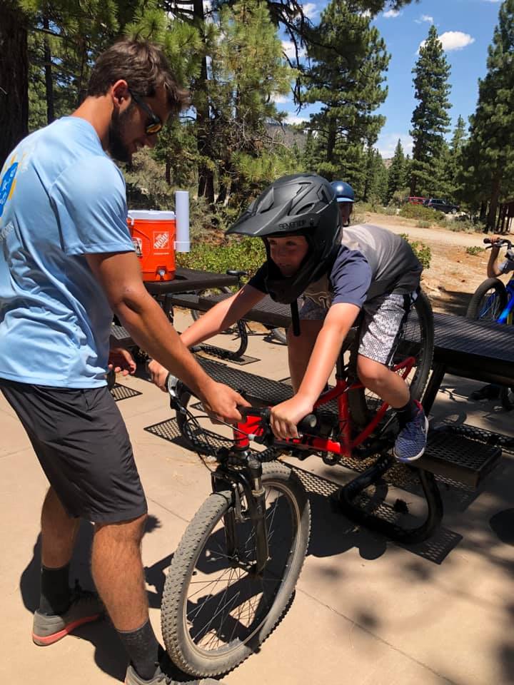 Camp counselor instructing a camper on mountain biking techniques
